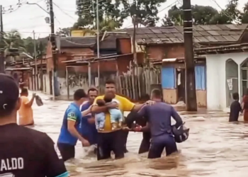 Vizinhos fazem corrente humana para ajudar pai a tirar gêmeos de casa alagada