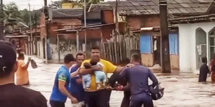 Vizinhos fazem corrente humana para ajudar pai a tirar gêmeos de casa alagada
