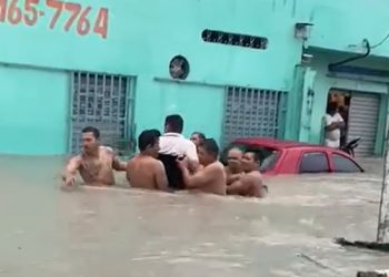 Moradores do Zumbi se unem para carregar cadeirante em rua alagada de Manaus
