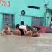 Moradores do Zumbi se unem para carregar cadeirante em rua alagada de Manaus
