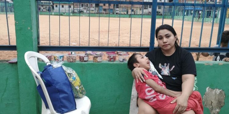Mãe vende bombons em Manaus para comprar cadeira de rodas após ser vítima de falsa médica